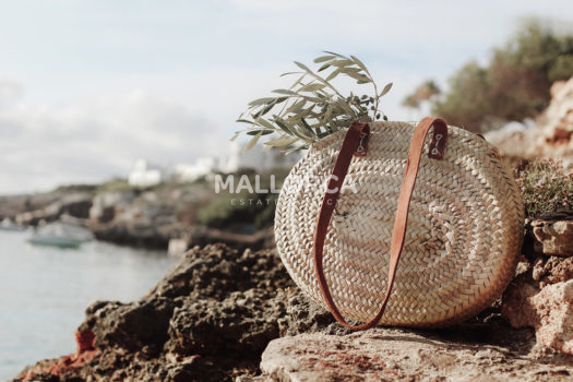 Basket with olive tree branches on beach rocks